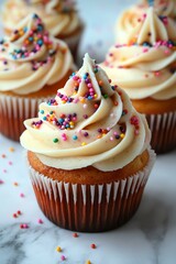 Delicious cupcakes with creamy frosting and colorful sprinkles on a marble table.