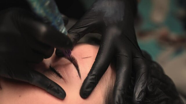 Beautician applying permanent eyebrow makeup on client