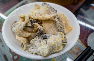 A plate of deep fried fish skin with a coating of seasoning.