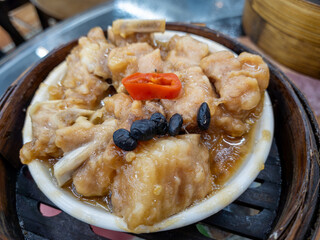 A dish of steamed spare ribs with black beans and chilli served in a bamboo steamer. A Chinese Dim Sum classic food.