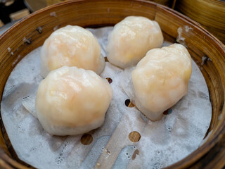 Close up of the classic Cantonese Dim Sum dish Har Gow, shrimp dumplings, steamed and served in a bamboo steamer.
