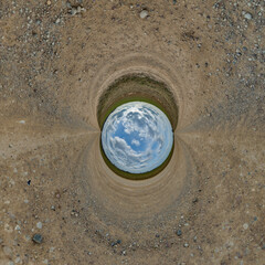blue hole sphere or globe little planet inside grass or sand or dry ground frame background with...