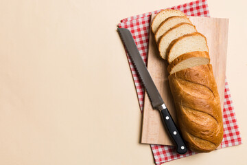Freshly baked bread cut with knife on a wooden board. top view Sliced bread and knife