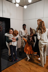 Family welcomes guests hugging and smiling with children in hallway during Christmas