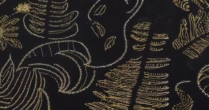 Anamorphic video of close-up of black fabric with a golden fractal design