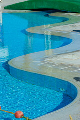  Curved turquoise swimming pool design with clear water reflects summer leisure and tropical relaxation vibes