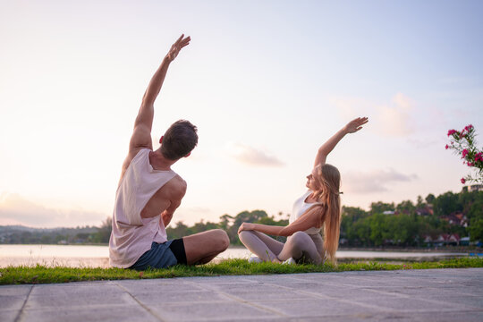 Couple Practicing Yoga by Tranquil Lakeside at Sunset for Wellness and Peace