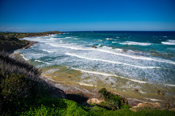 A wild beach with a rugged rocky coastline and powerful waves crashing against the shore in Northern Cyprus. Raw energy of nature and the untamed beauty of the Mediterranean Sea