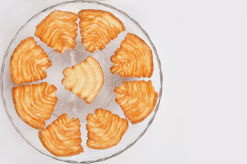 A top-down view of a glass plate filled with golden-brown palmiers, showcasing their flaky texture and spiral shape