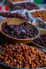 A variety of fresh and dried dates displayed in woven baskets at an outdoor market.