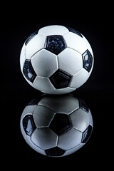 Fototapeta premium Classic Black and White Soccer Ball on a Reflective Black Background, Perfect for Sports Photography