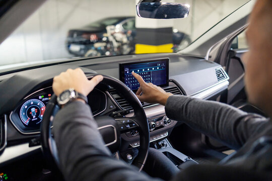 Cropped picture of a businessman typing directions on GPS display in his luxurious car.