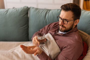 Sick Man takes medication prescribed by his physician. Unwell Man taking a pill and drinking a glass of water. Health, medicine, treatment concept