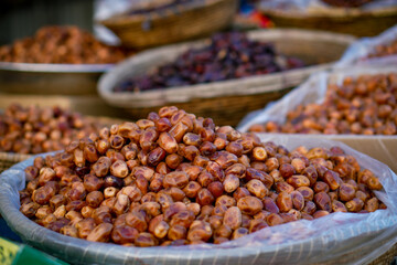 A variety of fresh and dried dates arranged in plastic-lined baskets at a market stall.