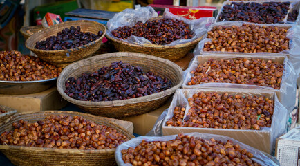 A colorful assortment of fresh and dried dates arranged in woven baskets and cardboard boxes at a local market.