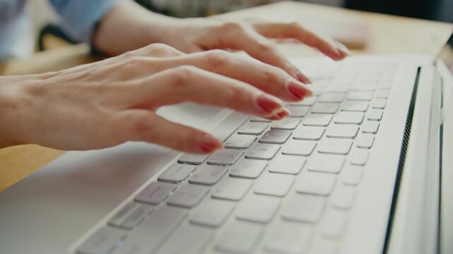 Well-groomed hands with neatly painted nails typing on laptop keyboard while working on task. Writing emails or drafting documents while focusing on productivity in professional workspace.