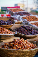 Various fresh and dried dates displayed in woven baskets at an outdoor market.