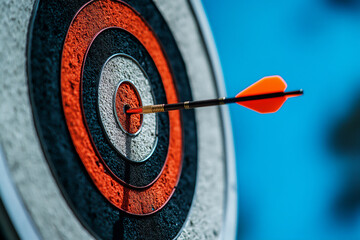 darts arrow hit the bullseye target with a blue sky background, close-up,