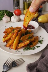 Golden of baked potatoes, seasoned with paprika and garlic, topped with fresh parsley and rich tomato sauce an irresistible homemade dish served fresh from the oven. vertical photo