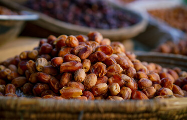 A detailed close-up of fresh dates in a woven basket, with various dried dates in the background at an outdoor market.