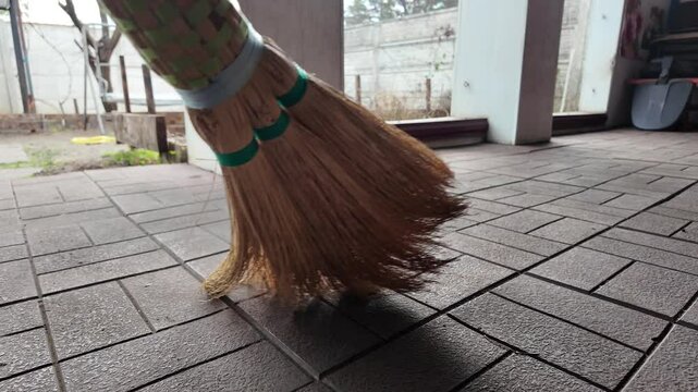 straw broom. broom in hands. man sweeps floor with broom. slow motion video.
