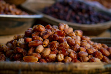 A close-up of a heap of ripe dates displayed in a woven basket at a market.
