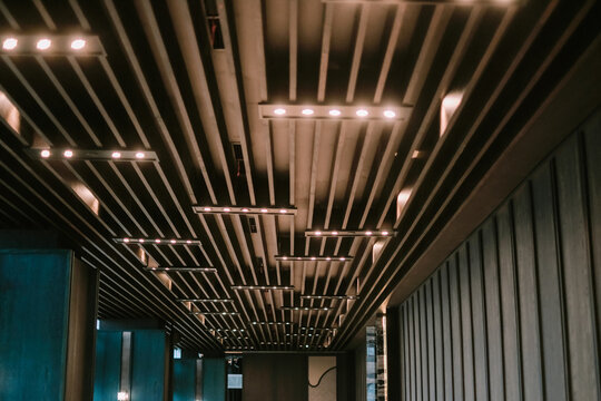 Architectural ceiling design with parallel wooden beams and lighting fixtures