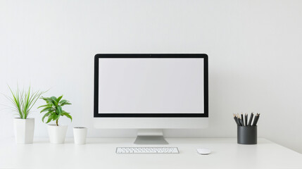 Minimalist workspace with a blank computer screen, plants, and stationery on a white desk, copy space