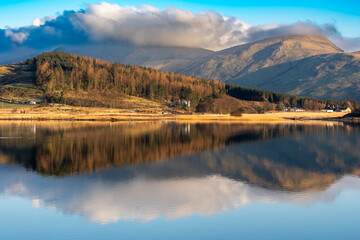 Reflections of Snowdonia mountains during golden hour in Llyn y Gadair
