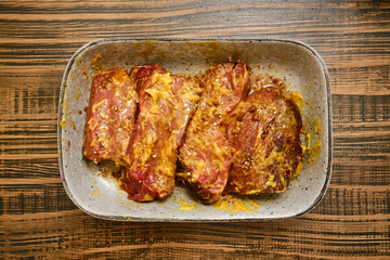 Raw beef flat iron steak marinated in mustard, soy sauce and spice blend in ceramic bowl