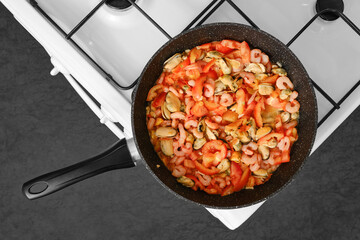 Fresh seafood stir fry with shrimp, mussels, and tomatoes on a gas stove