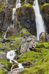 Waterfall and basalt rocks covered by moss. Seydisfjordur. Iceland