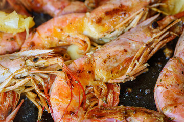 Langoustine on frying pan with butter, lemon and garlic. Fried shrimps. Grilled large shrimps, longoustine cooked in a frying pan with spices.