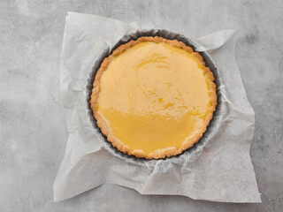 Delicious lemon tart resting on baking paper in a cake pan