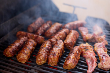 (Mici), traditional Romanian meat dishes on a grill during the cooking process