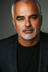 Fototapeta premium Confident middle aged man in black suit with stylish haircut and strong gaze in professional portrait