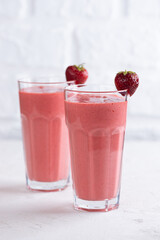 Strawberry cold cocktail, smoothie from strawberries, coconut cream, green buckwheat in two glasses. Lactose and sugar free. Vertical orientation.