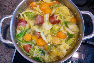 A pot of soup with vegetables and meat in it