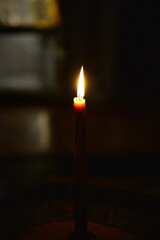 Fototapeta premium Candle burning in the dark with focus on single candle in foreground.