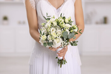 Bride with beautiful wedding bouquet on light background, closeup