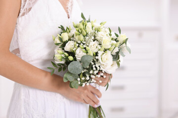 Bride with beautiful wedding bouquet on light background, closeup. Space for text