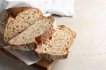 Cut loaf of fresh bread on table, closeup
