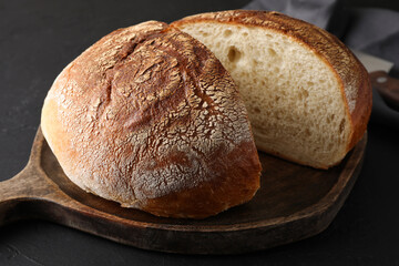 Cut loaf of bread on black table, closeup