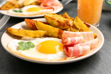 Tasty brunch. Fried egg, potato and bacon on dark textured table, closeup