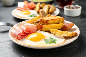 Tasty brunch. Fried egg, potato and bacon on dark textured table, closeup