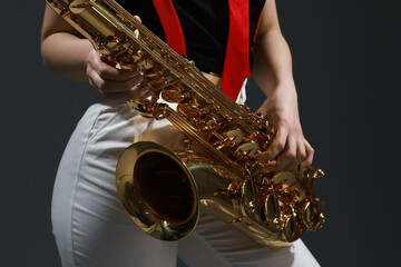 Professional musician with saxophone on grey background, closeup