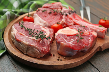 Pieces of raw beef, tomatoes and spices on wooden table, closeup
