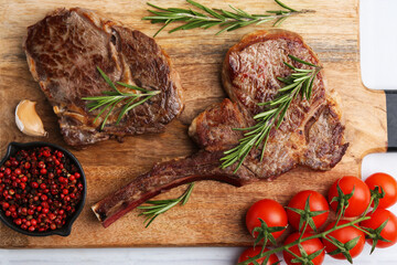Pieces of delicious beef meat, spices and tomatoes on white table, top view