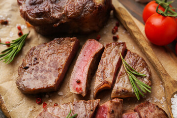 Pieces of delicious beef meat, spices and tomatoes on table, closeup