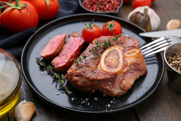 Pieces of delicious beef meat, spices and tomatoes on wooden table, closeup
